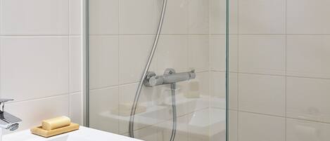Une salle de bain moderne avec une douche à parois de verre, un lavabo blanc et un miroir.
