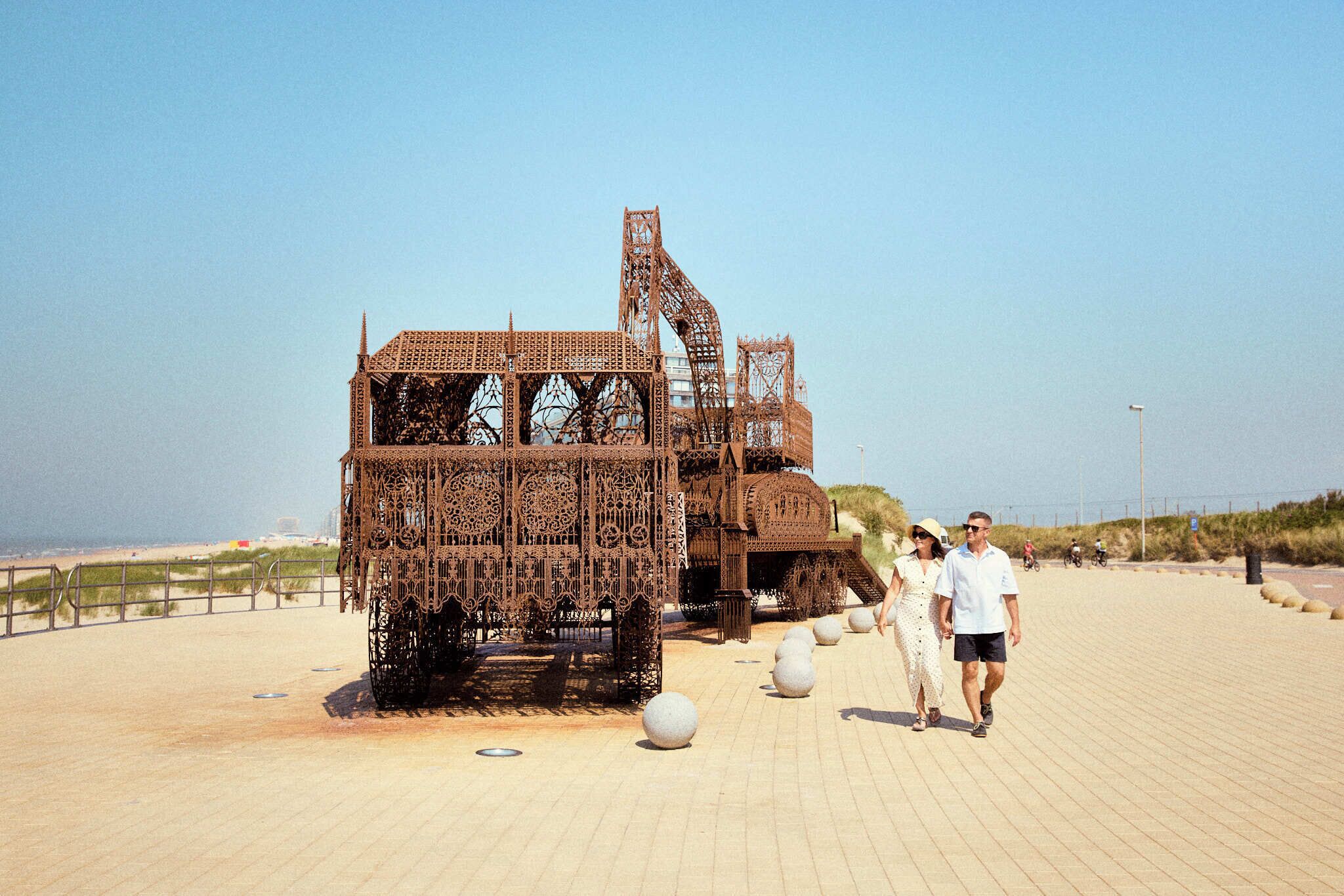 A large metal sculpture on a paved walkway.