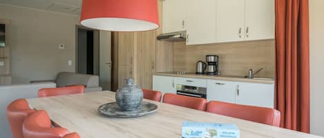 A dining area with a table, chairs, a vase, and a box of 'H. Liday Suites' welcome cards.