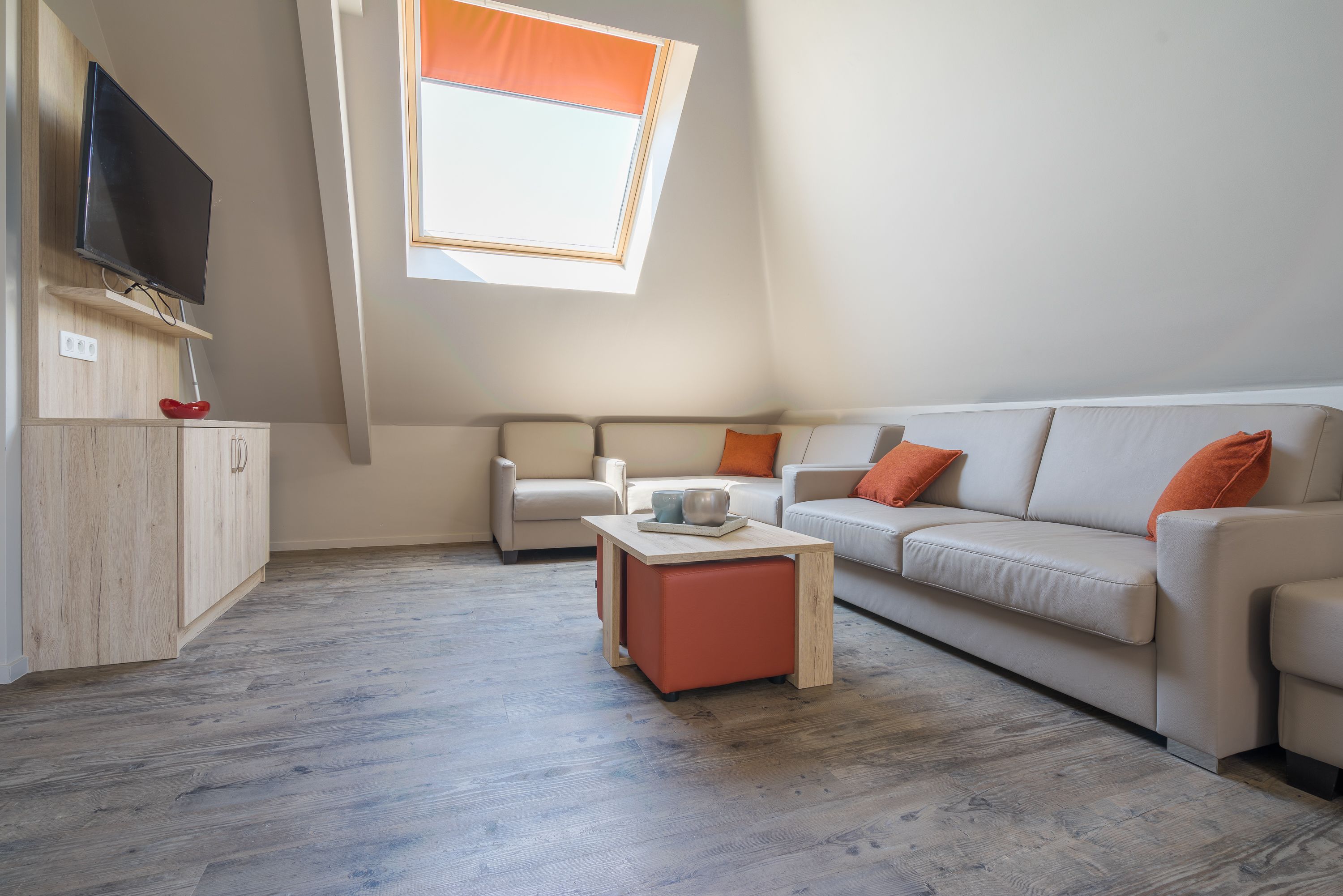 A modern living room with a sofa, a coffee table, and a TV mounted on the wall.