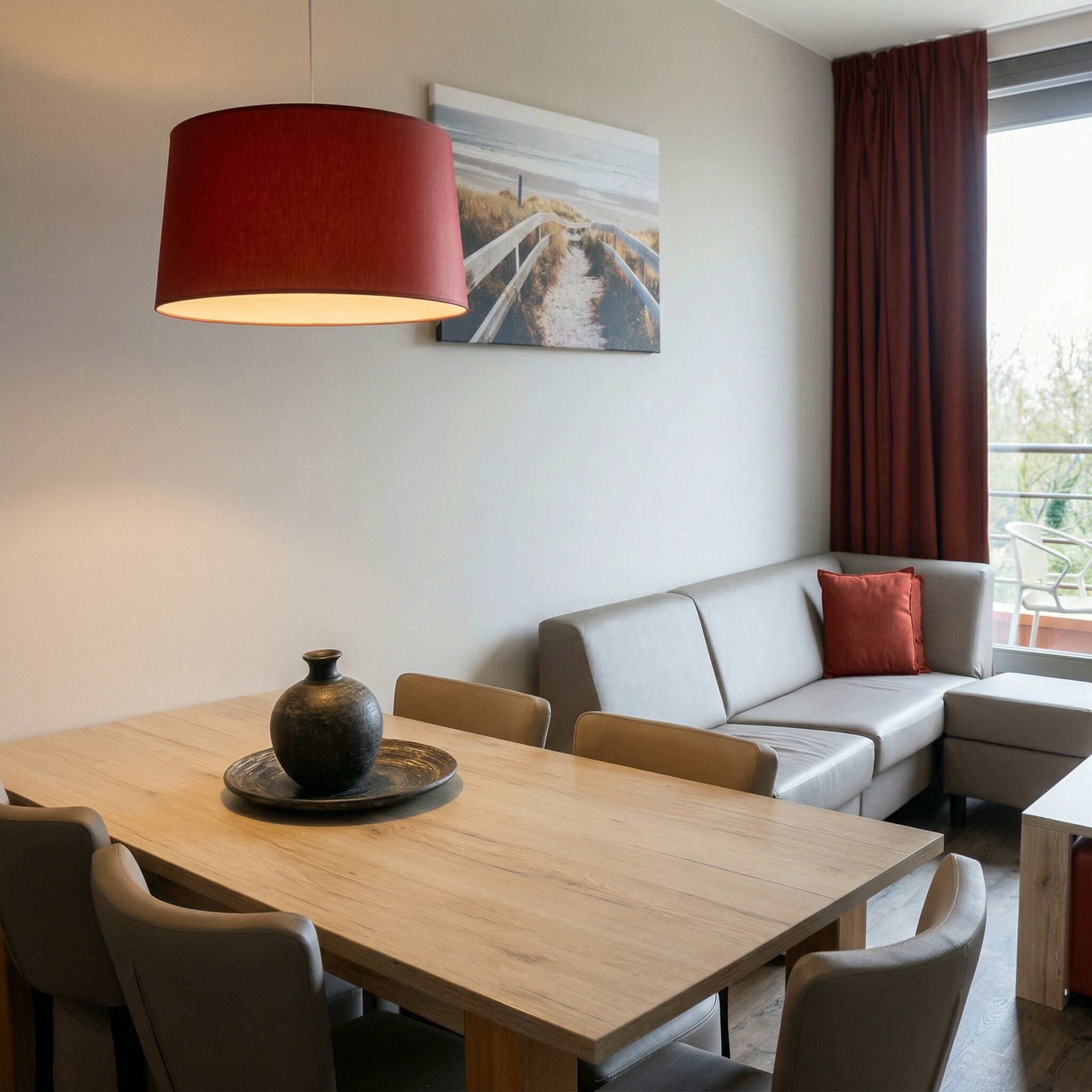 Ein modernes Wohnzimmer mit Esstisch, Sofa und einer großen, roten Pendelleuchte.