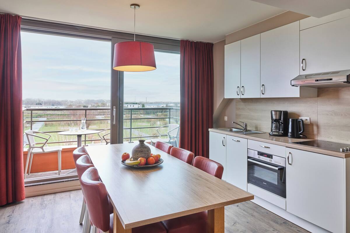 Une cuisine moderne avec un coin repas, de grandes fenêtres et une vue sur la campagne.