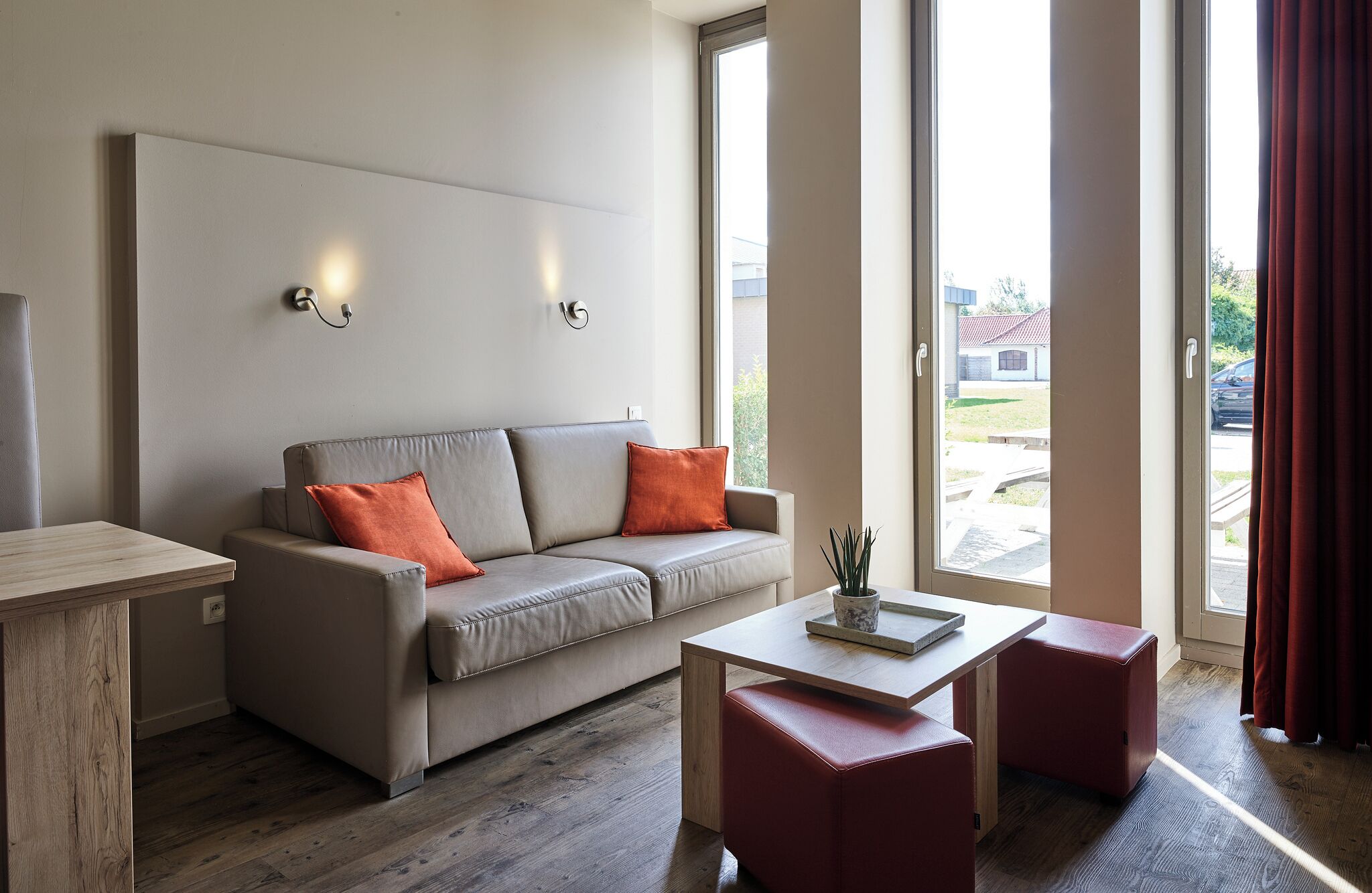 Uma sala de estar moderna com um sofá, uma mesa de centro e vista para o exterior.