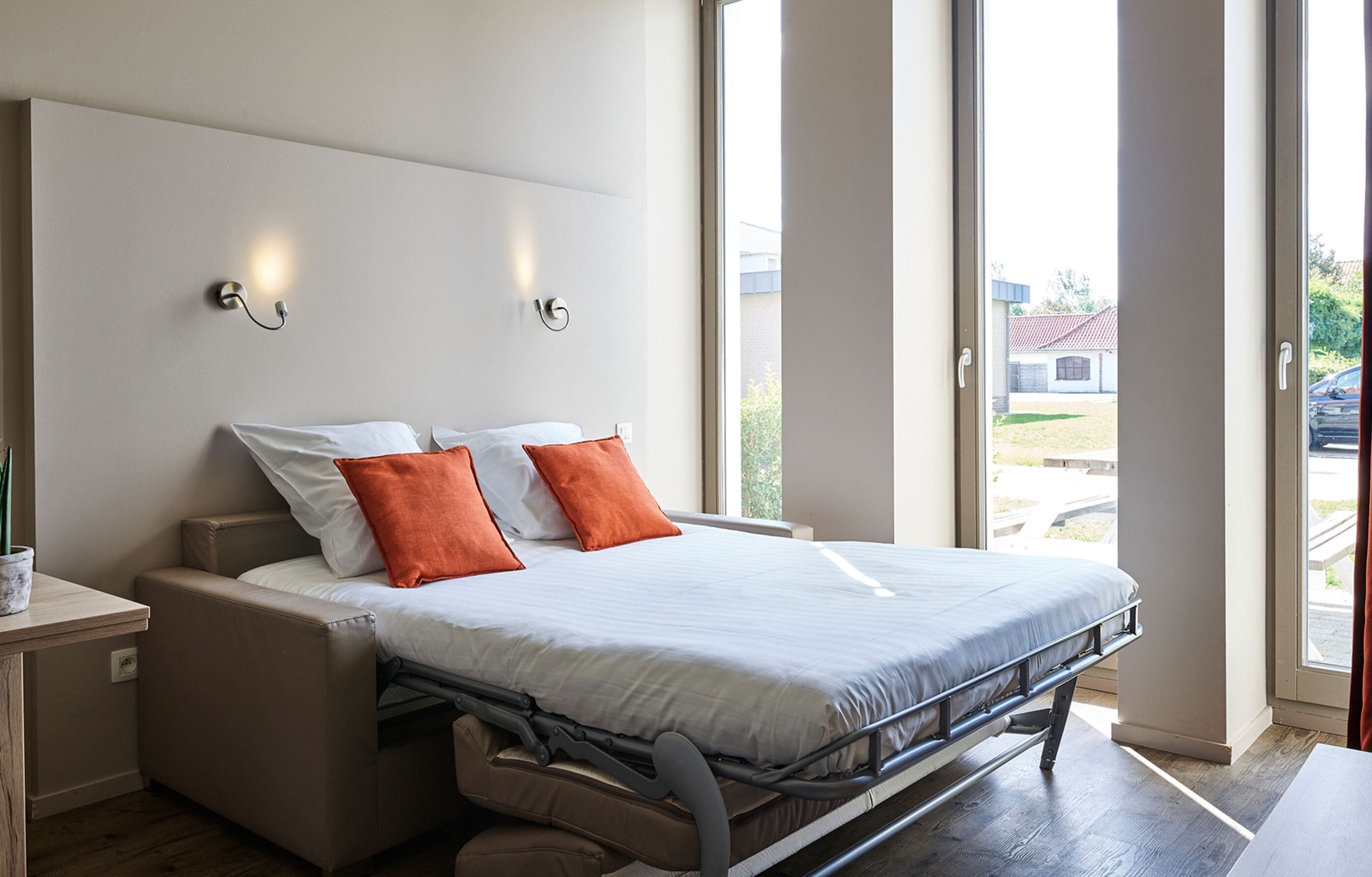 A modern bedroom with a bed, nightstands, and a window with a view of the outside.