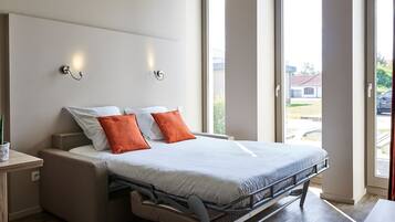 A modern bedroom with a bed, nightstands, and a window with a view of the outside.