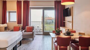 Een hotelkamer met een bed, een bureau met stoelen, een eettafel en een balkon met uitzicht.