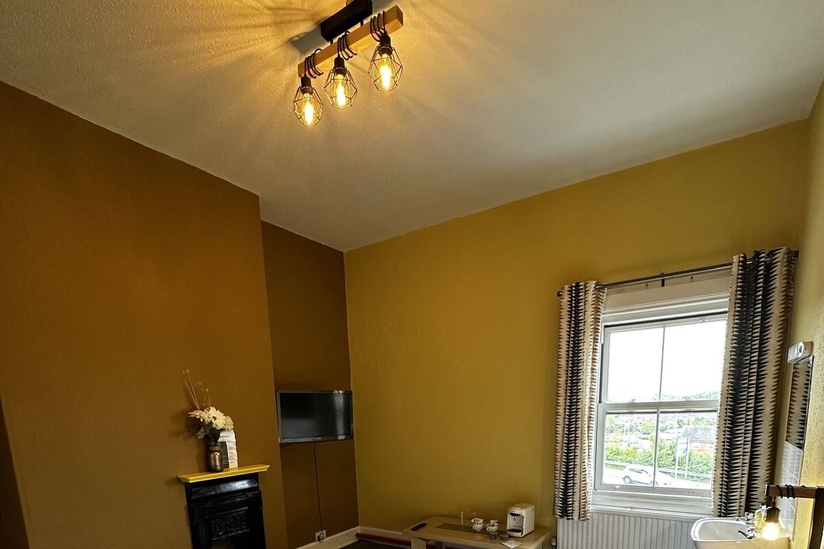 A hotel room with a large bed, a desk, a television, and a window with curtains.