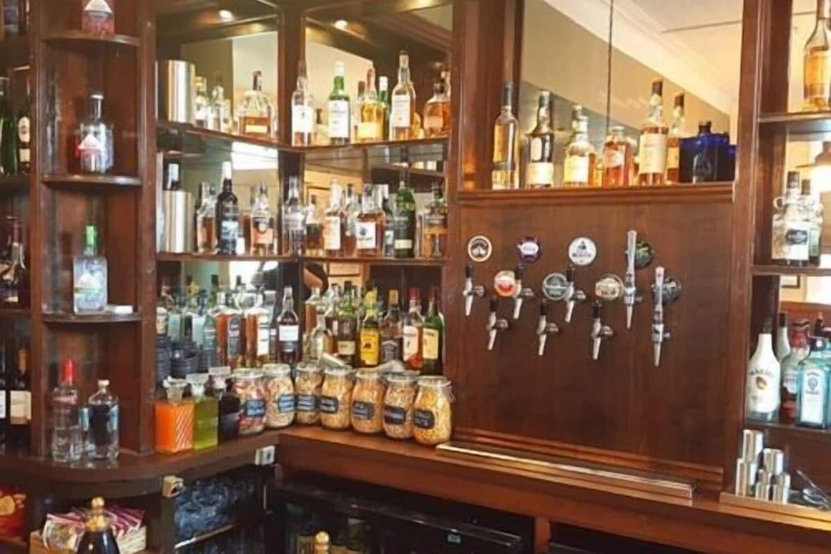 A bar area with shelves of liquor bottles and a wall of beer taps.