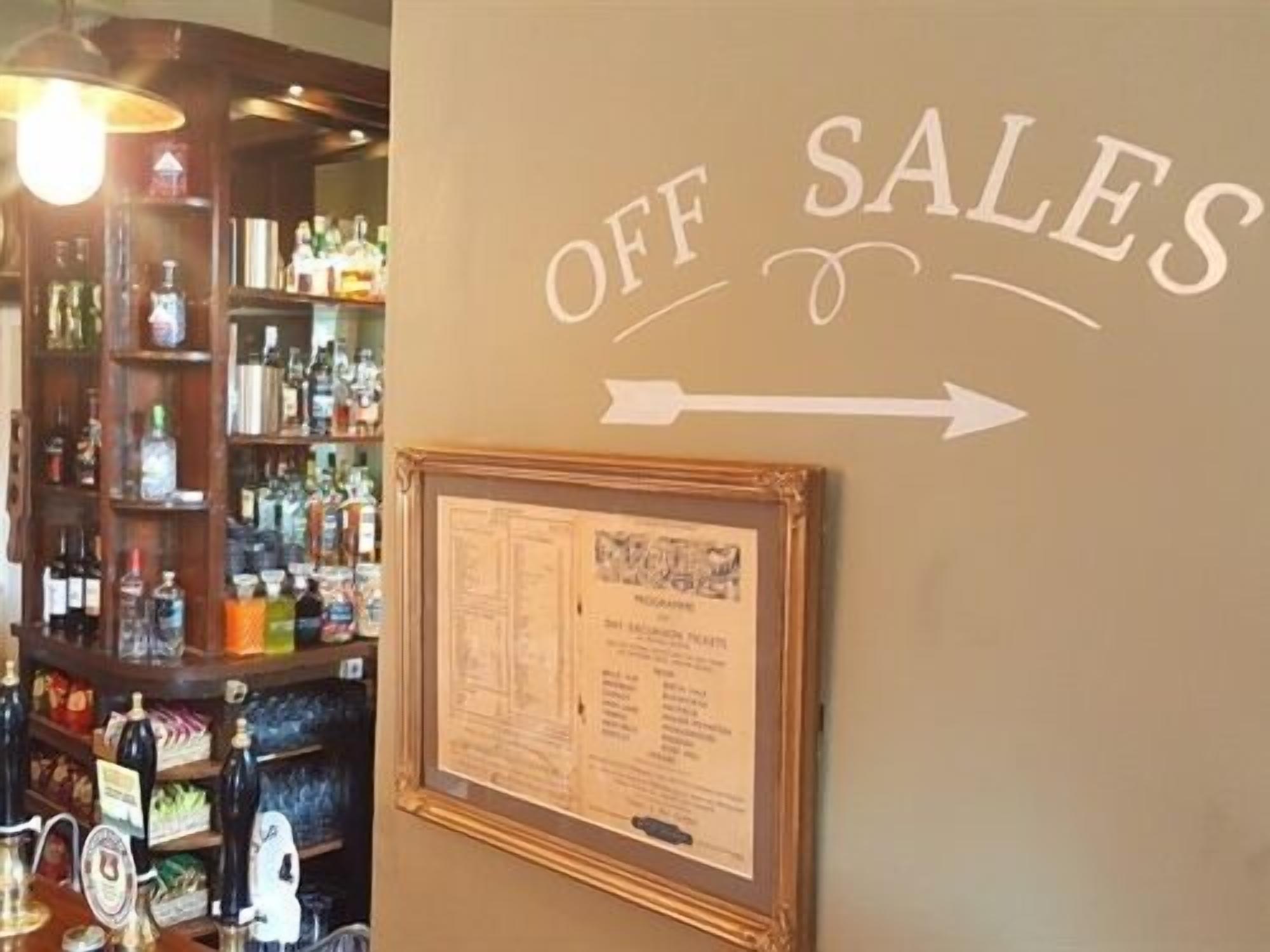 Un espace bar avec une pancarte indiquant « VENTE À EMPORTER » et un menu encadré accroché au mur.