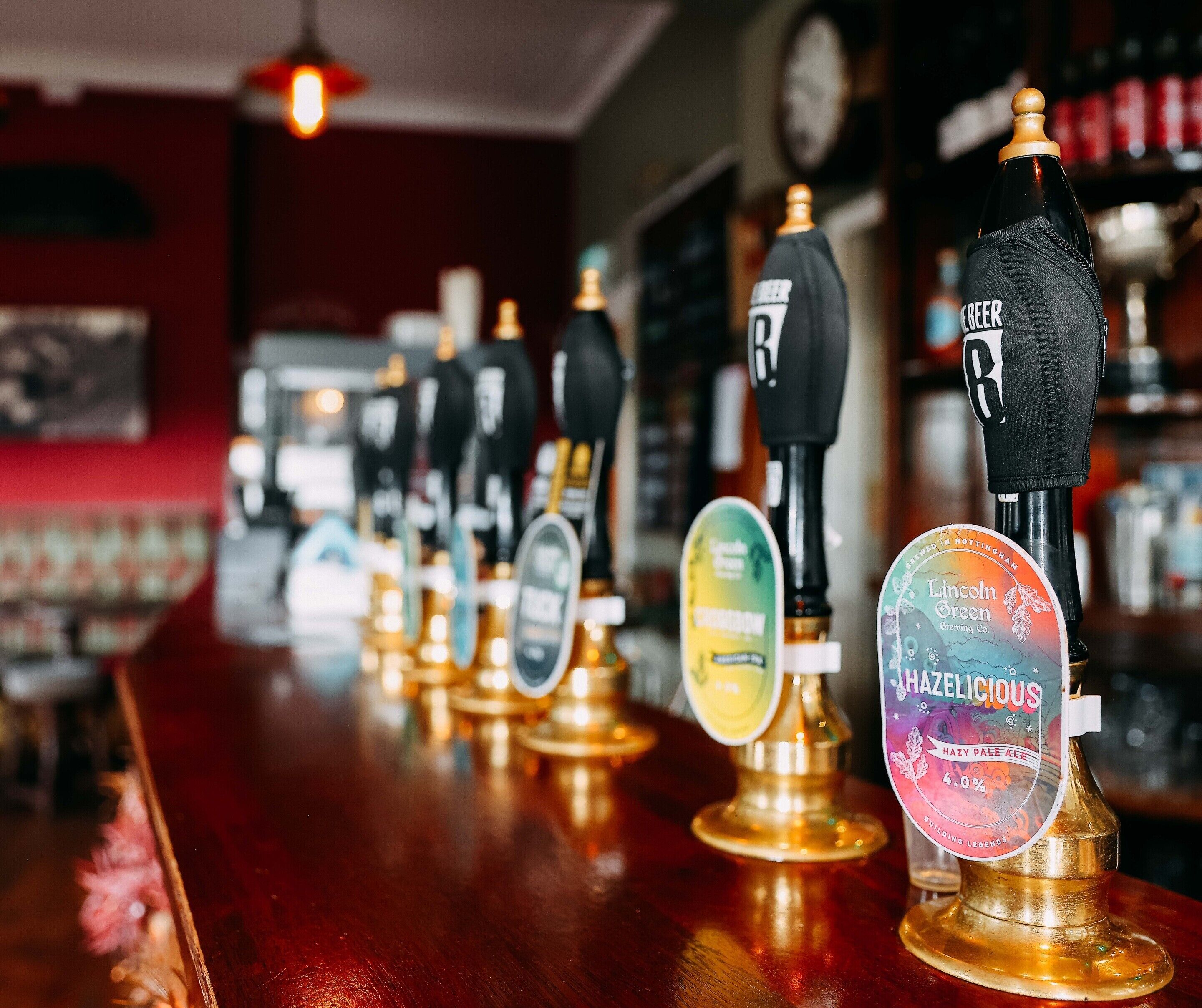 Un bar con varias llaves de cerveza, incluyendo una llave con la marca Lincoln Green.