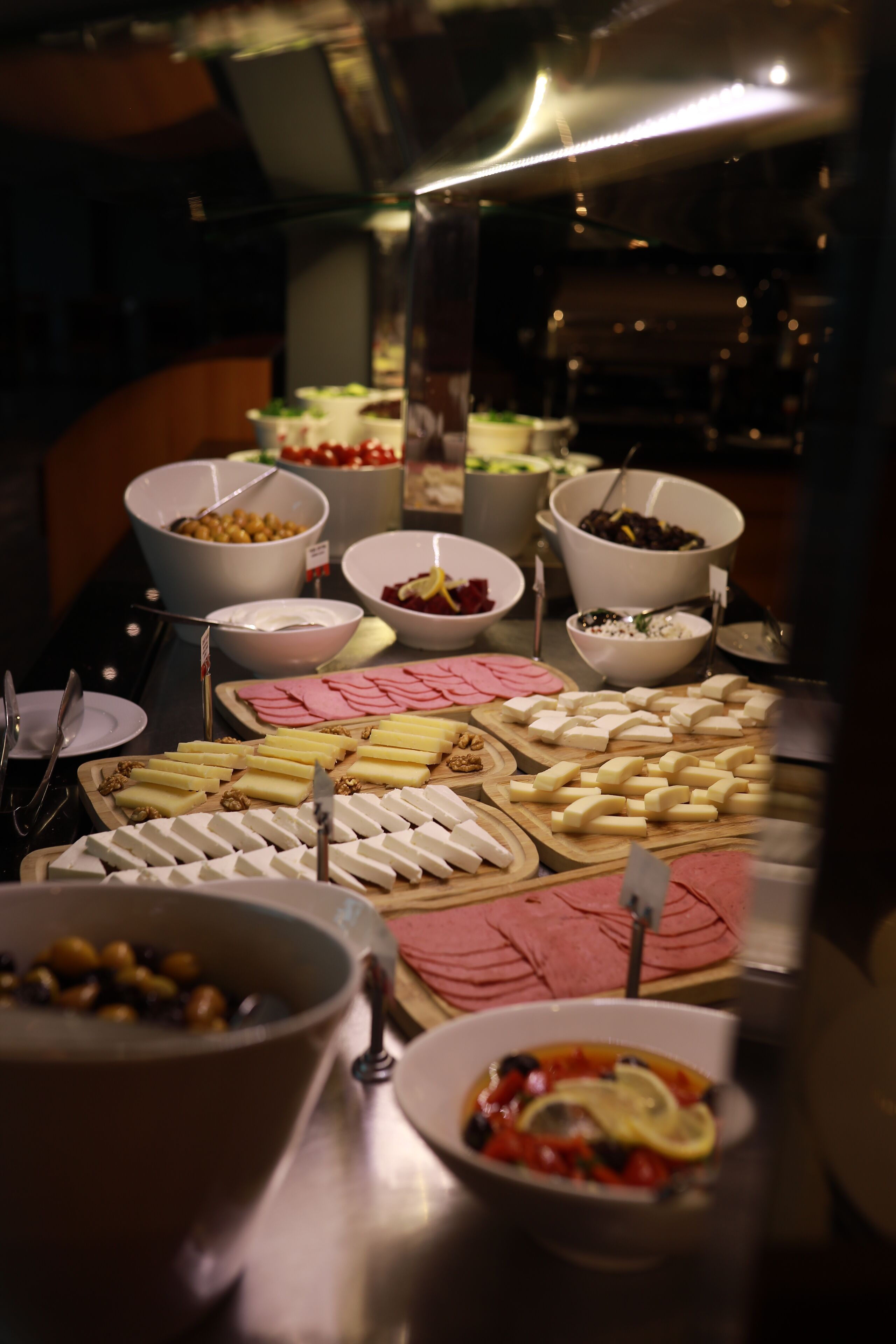 Buffet com diversos itens, incluindo queijos, carnes e frutas.