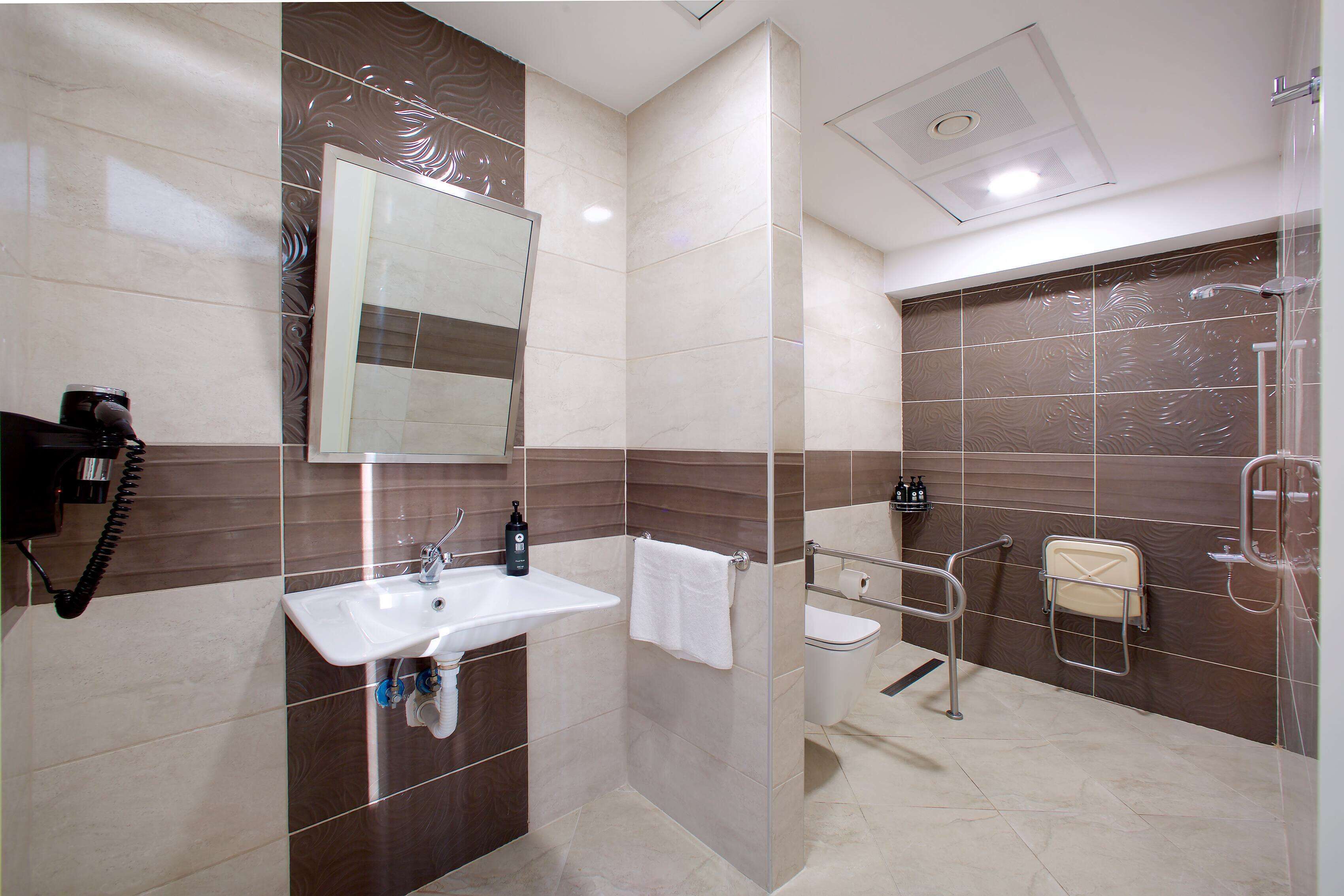 Un baño moderno con lavamanos, espejo, inodoro y zona de ducha.