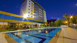 A modern hotel with a swimming pool, outdoor seating area, and a well-lit facade. - Ramada by Wyndham Soma (Soma)
