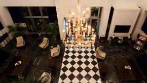 A lobby with a black and white checkered floor, a chandelier, and seating areas. - Ramada by Wyndham Soma (Soma)