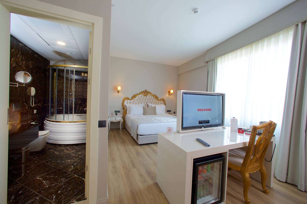 Une chambre d’hôtel comprenant un lit, un bureau avec une télévision, une douche et des toilettes.