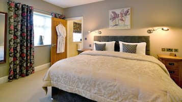 Une chambre à coucher avec un grand lit, une table de chevet en bois, une commode, un miroir et une fenêtre avec des rideaux.
