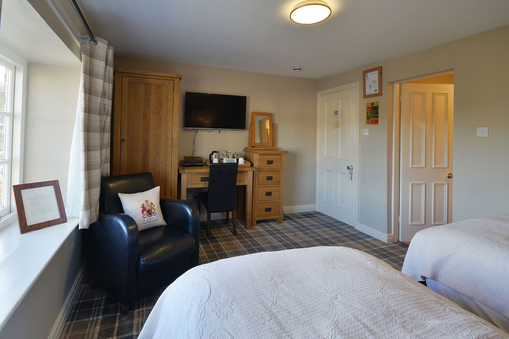 A hotel room with a bed, a desk with a chair, a television, and a wardrobe.