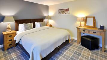 A neatly arranged bedroom with a bed, bedside tables, a desk, and a chair.