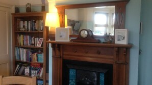 Una habitación con chimenea, una estantería y un espejo.
