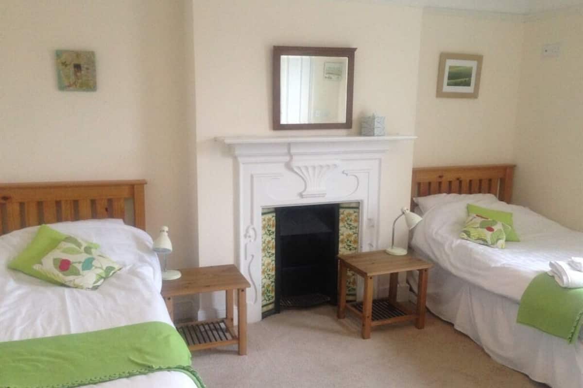 A room with two beds, a fireplace, and a small table.