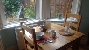 Una mesa de comedor dispuesta con platos, cubiertos y vasos, con sillas alrededor.