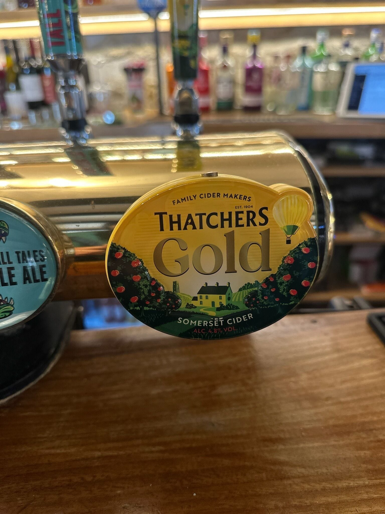 Un grifo con la etiqueta 'Thatchers Gold Somerset Cider', que indica 'Elaborantes de sidra familiares' y 'Fundada en 1904'.