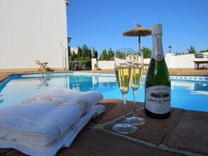 Escena junto a la piscina con una botella de champán Brut, dos copas y una toalla.