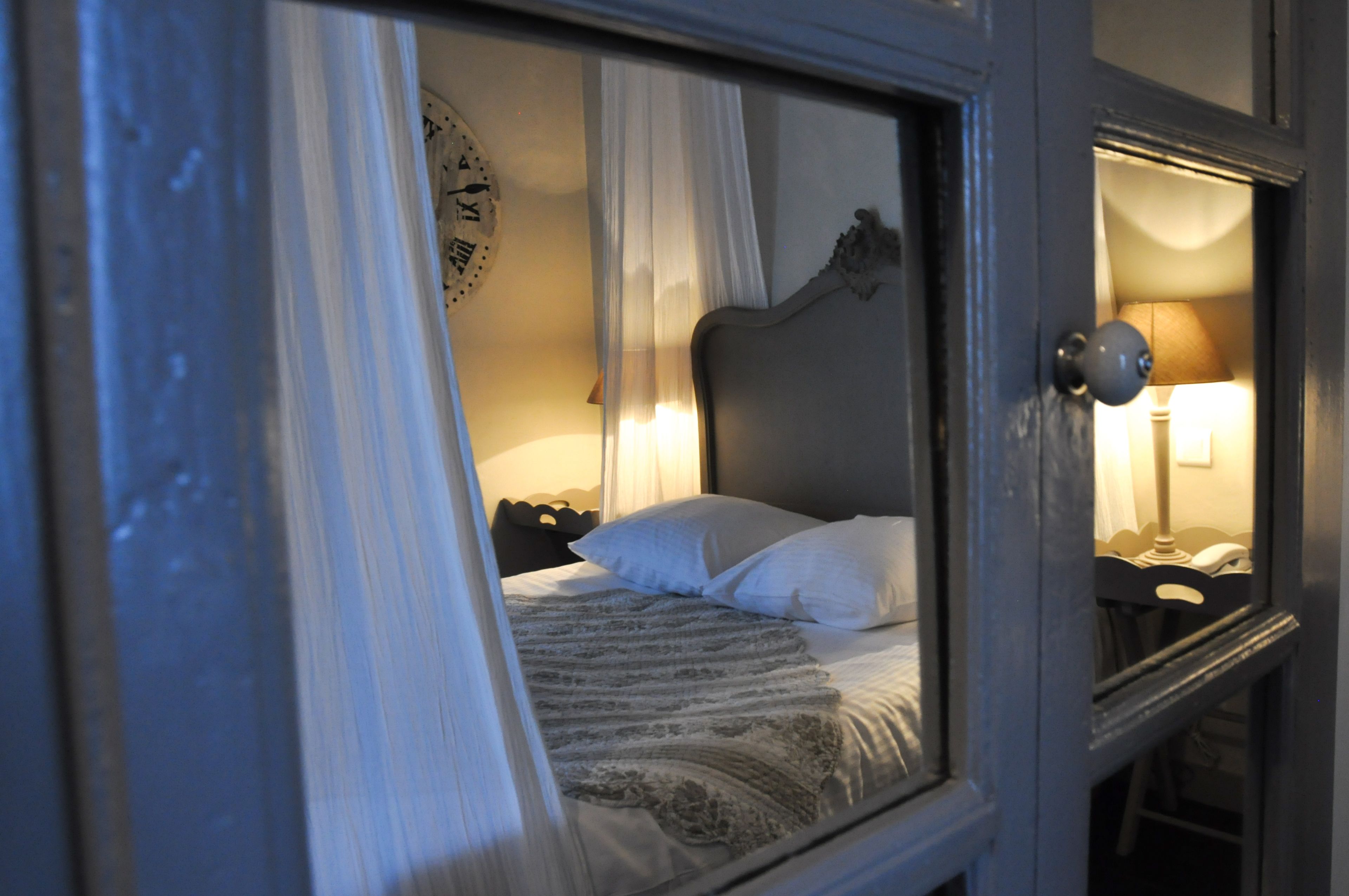 A bedroom with a bed, a nightstand, a lamp, and a clock on the wall.
