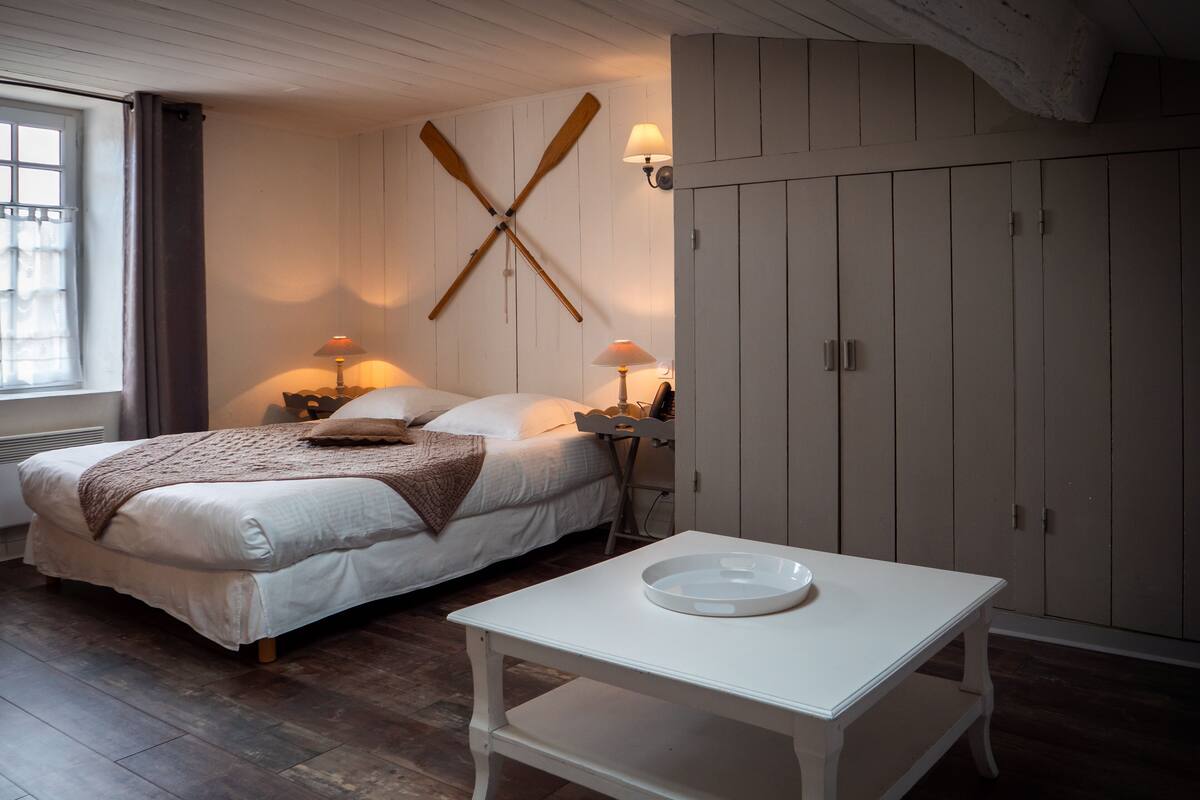 Ein Schlafzimmer mit einem Bett, Nachttischen mit Lampen, einem weißen Tisch, Holzboden und einem Kleiderschrank.