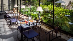 An outdoor dining area with tables and chairs, surrounded by lush greenery. - La Maison Douce (Saint-Martin-de-Re)
