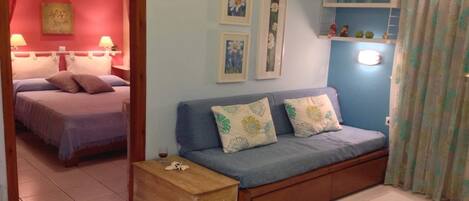 A cozy bedroom with a bed, a sofa, and a nightstand.