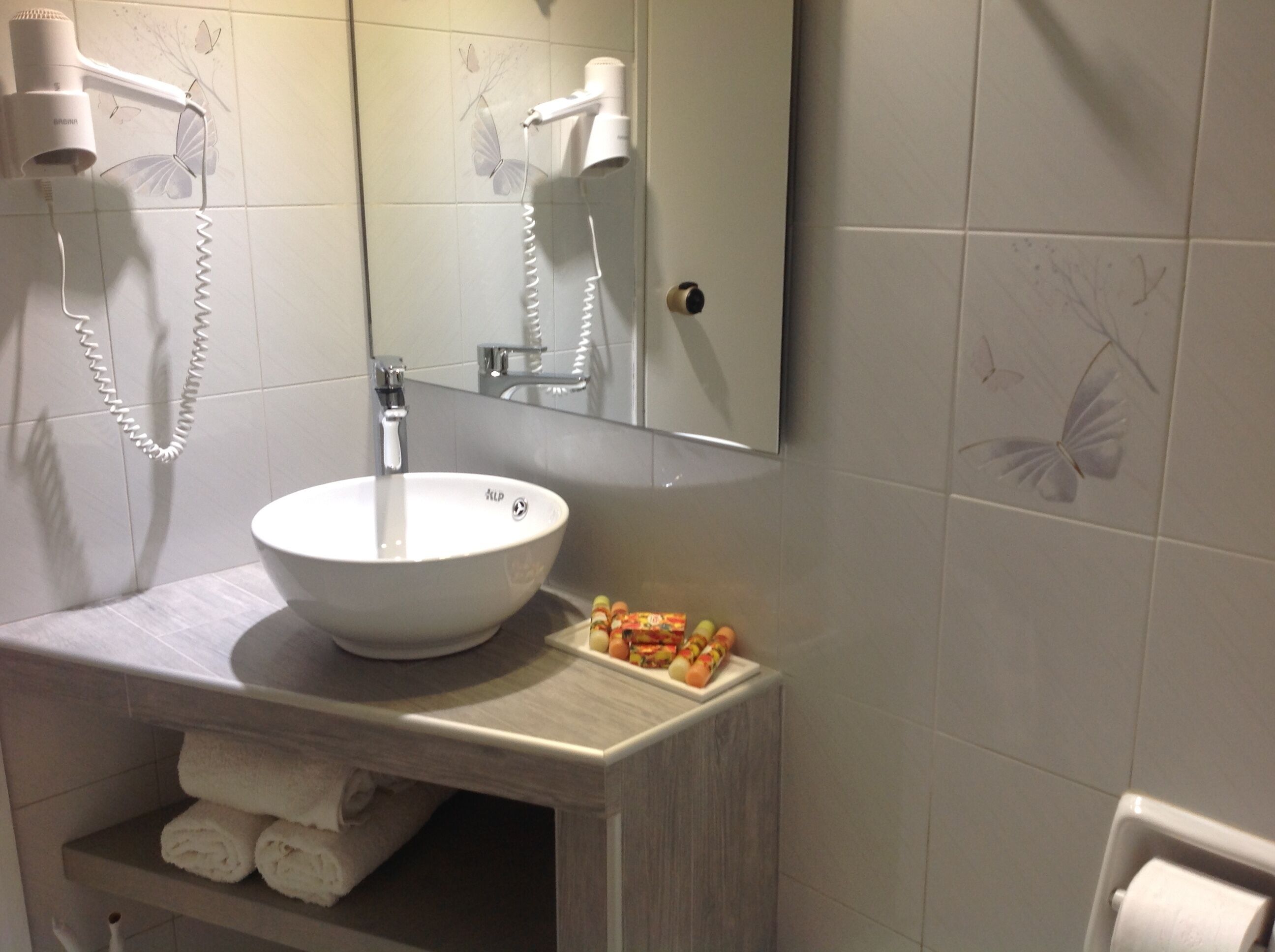 A bathroom with a white sink, a mirror, and a towel rack.