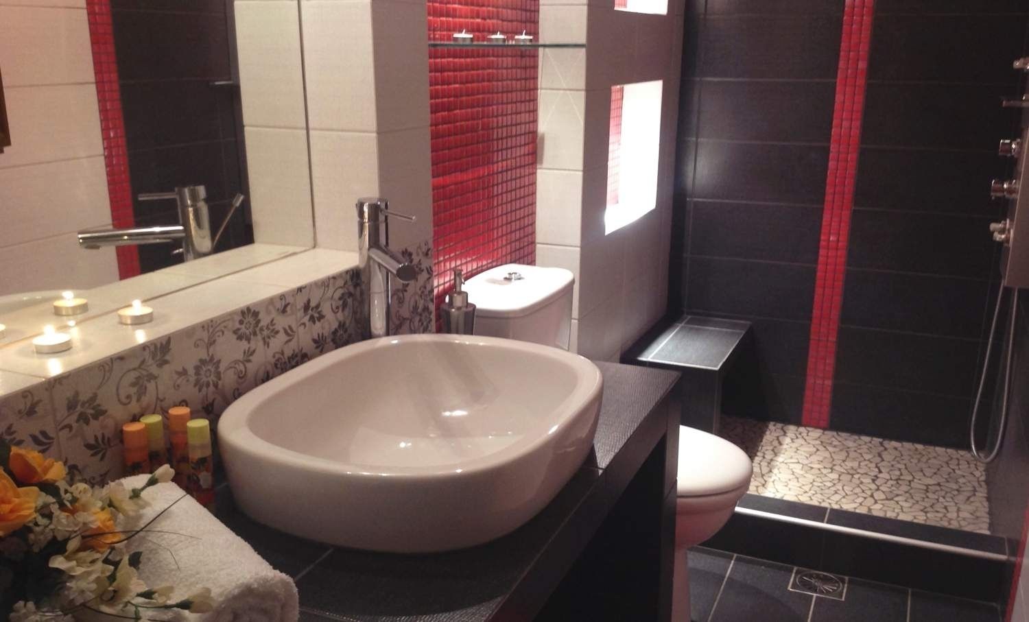 A modern bathroom with a large freestanding sink, a toilet, and a shower area.