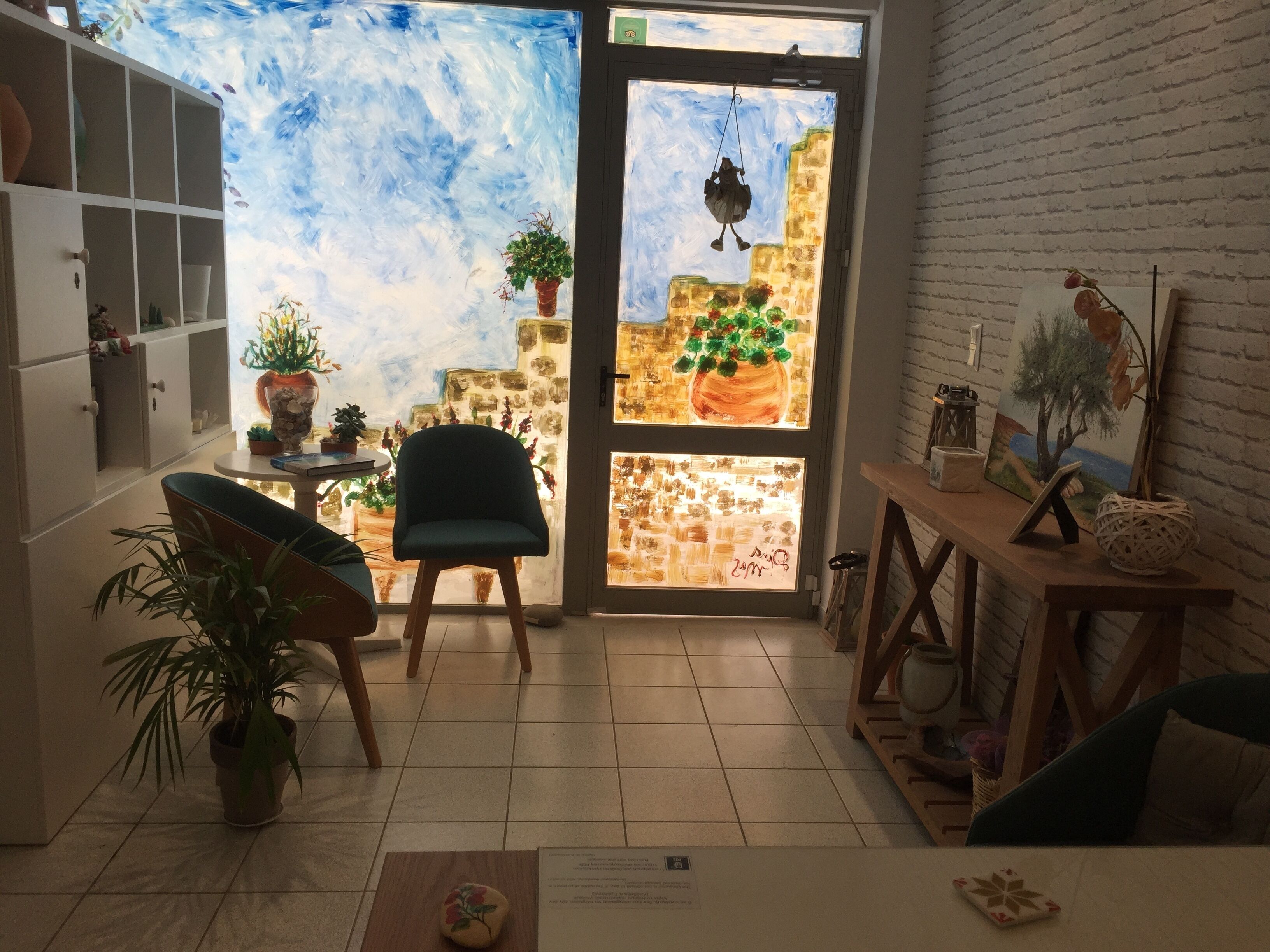 Un cuarto acogedor con vista a un paisaje pintado que se ve a través de una puerta, una silla, una mesita y una planta en maceta.
