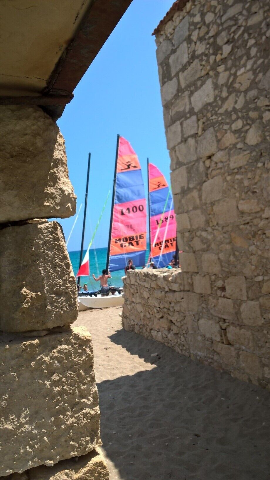 A stone building with a narrow passageway leading to a beach.