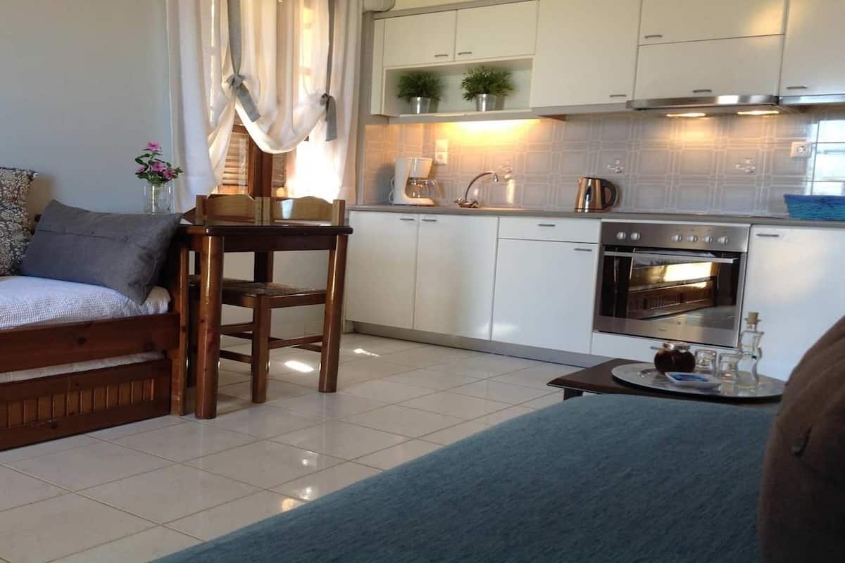 Una cocina compacta con armarios blancos, horno integrado y cafetera.