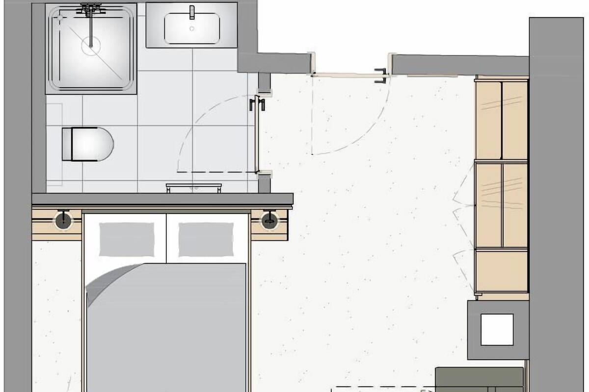 Ein Grundriss eines Hotelzimmers mit einem Bett, einem kleinen Badezimmer, einer Küchenzeile und einer Sitzecke.