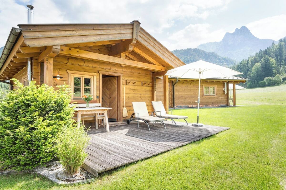 Eine Holzhütte mit einer Terrasse, einem Tisch mit Stühlen und einem kleinen Garten.