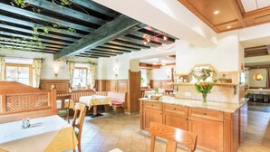 A cozy restaurant with wooden furniture, a central island, and a rustic ceiling. - Hotel Vitaloase zu den drei Brüdern (Unken)
