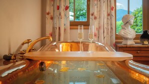A bathroom with a bathtub, a wooden tray, and two glasses of water. - Hotel Vitaloase zu den drei Brüdern (Unken)