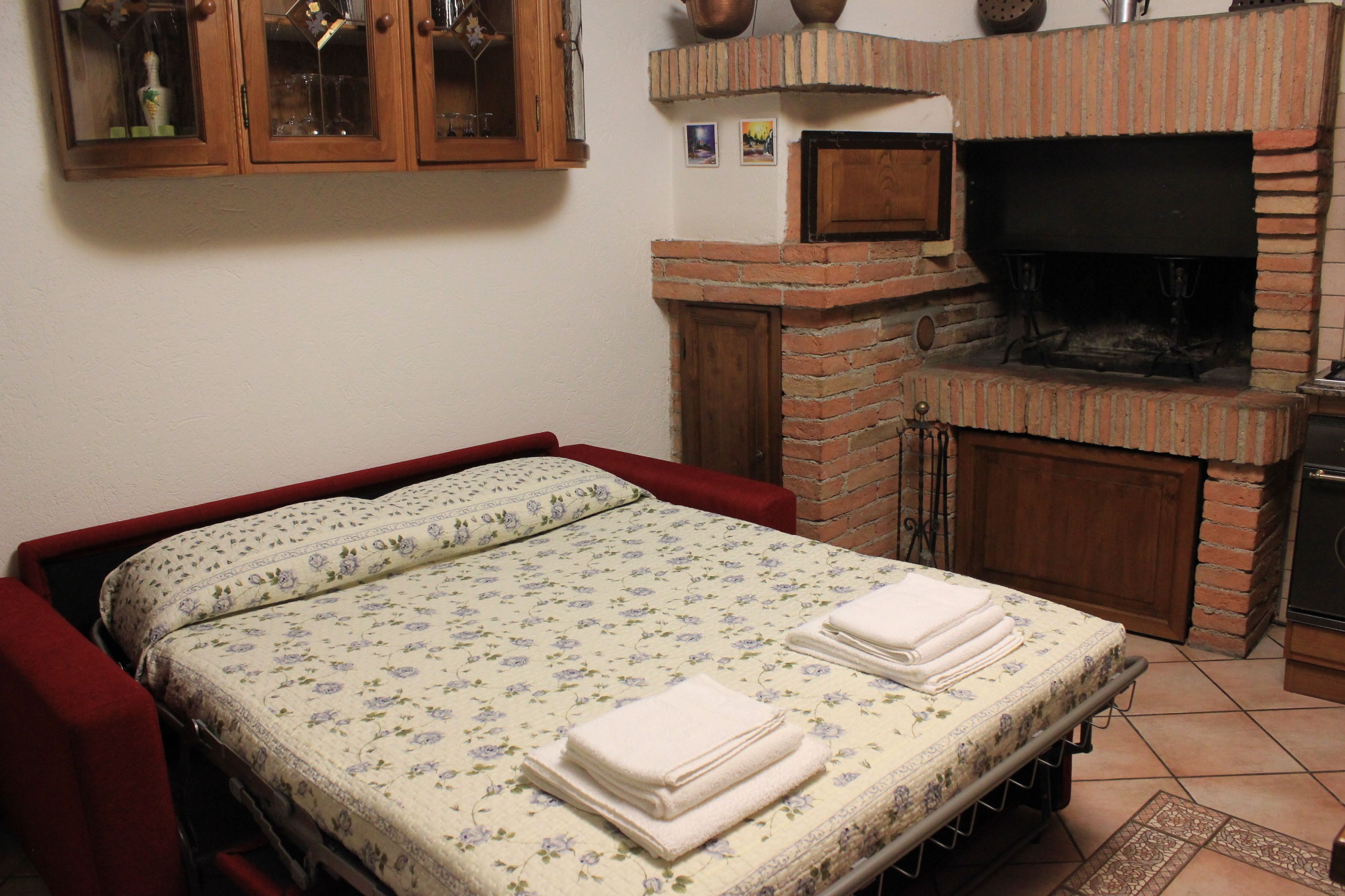 Un dormitorio con cama, chimenea de ladrillo y televisor.