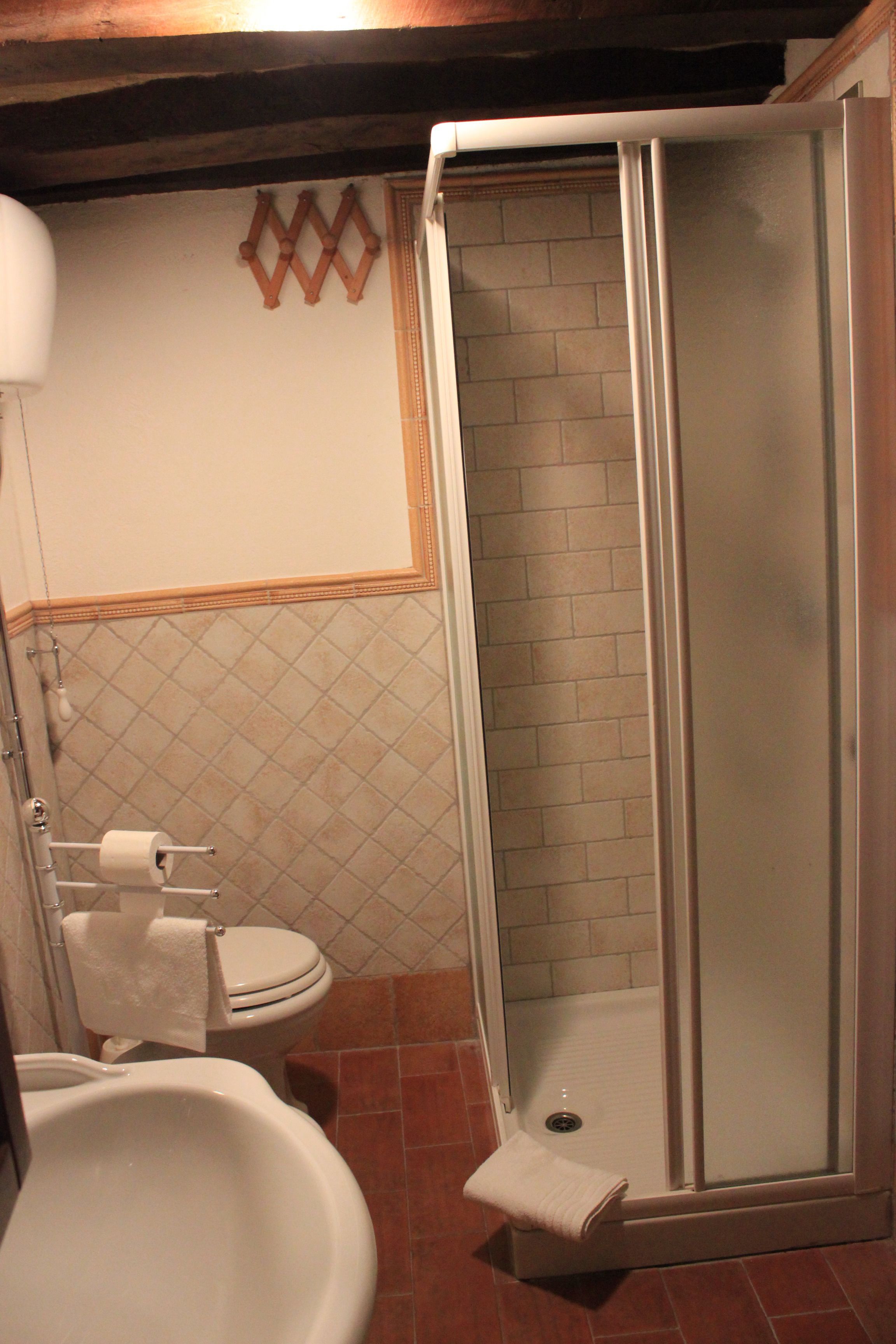 A bathroom with a toilet, bidet, and a glass-enclosed shower stall.