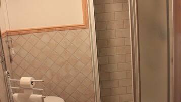 A bathroom with a toilet, bidet, and a glass-enclosed shower stall.
