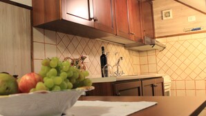 A kitchen with wooden cabinets, a tiled backsplash, and a countertop with a bowl of fruit. - Il Focolare (Todi)