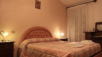 Ein Schlafzimmer mit einem großen Bett, zwei Nachttischlampen, einem Holznachttisch und einem Spiegel an der Wand.