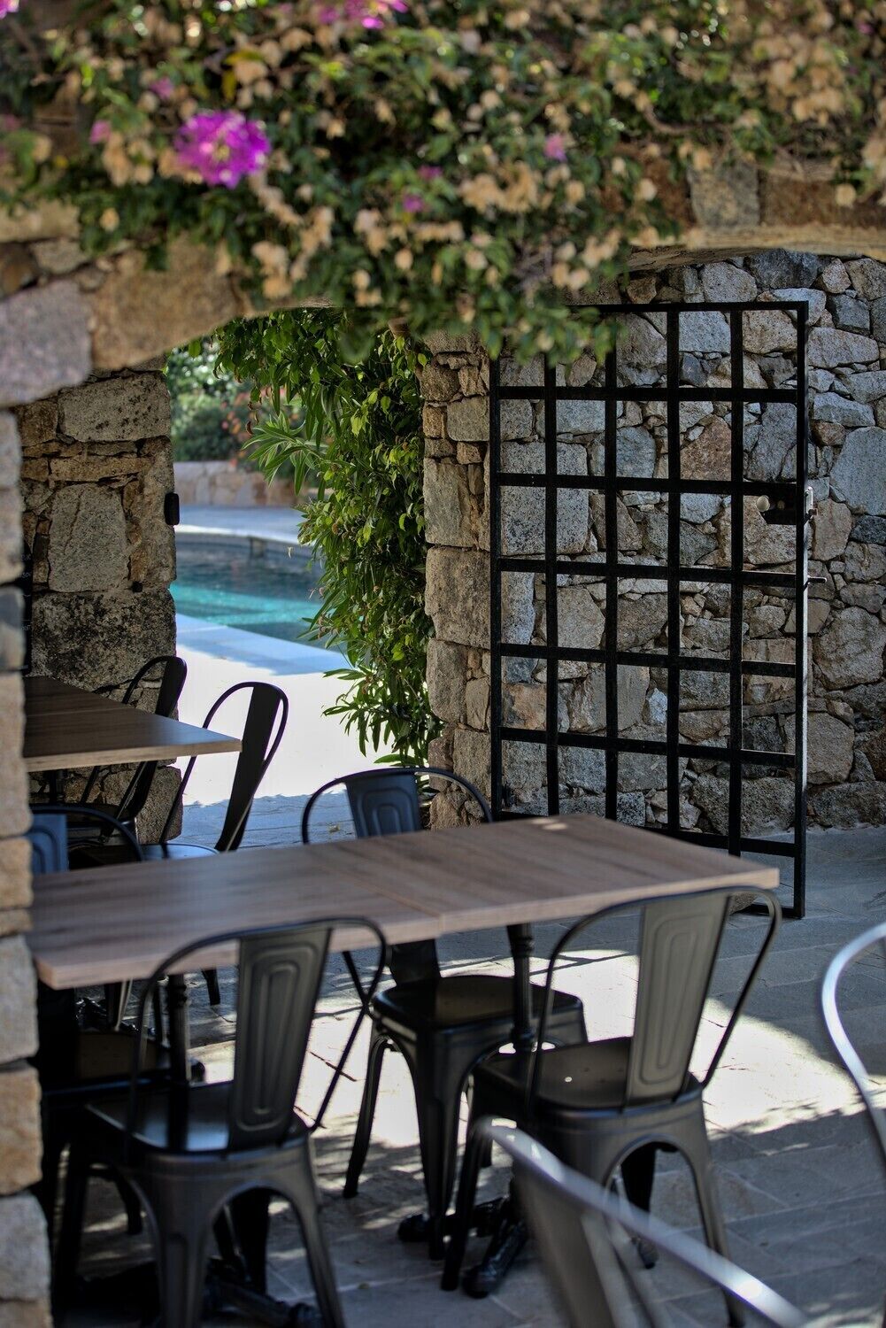 Eine Außenpatio mit Steinmauern, einem Pool und einem Metallgitter.