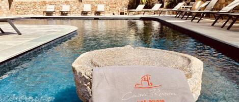 A pool area with lounge chairs and a towel with text.