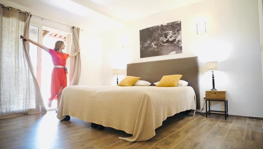 A hotel room with a bed, a nightstand, a lamp, and a painting on the wall.