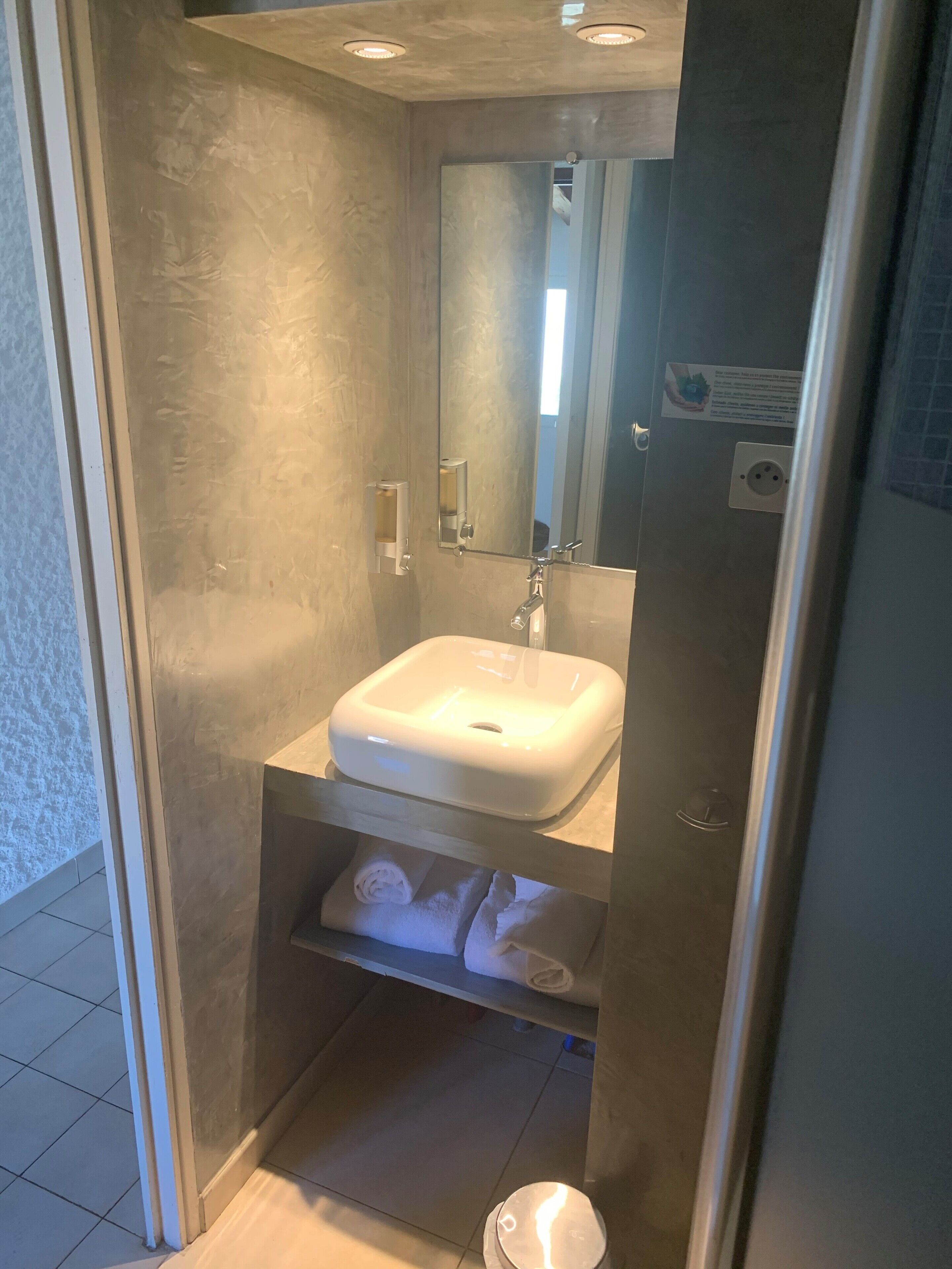 Une petite salle de bain avec un lavabo blanc, un miroir et une étagère à serviettes.