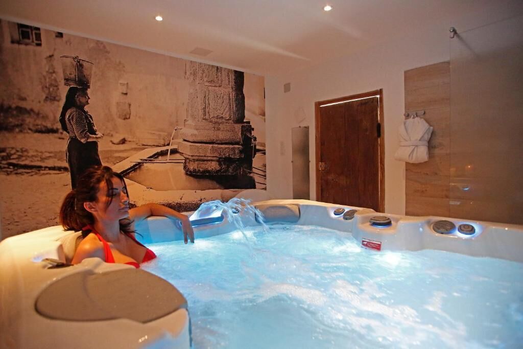 Ein Wellnessraum mit Whirlpool, einer Holztür und einem Handtuchhalter.